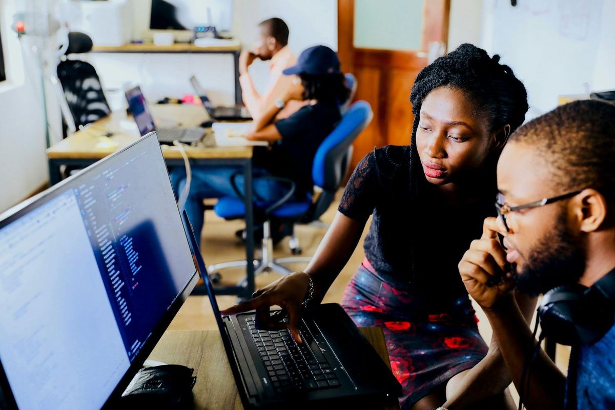 Two colleagues look at a laptop together in an office